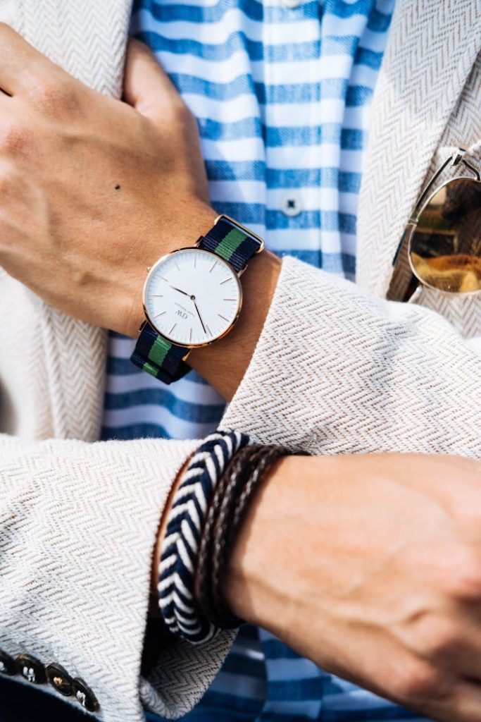 Close-up of a fashionable mans wrist showcasing a striped watch and bracelets.
